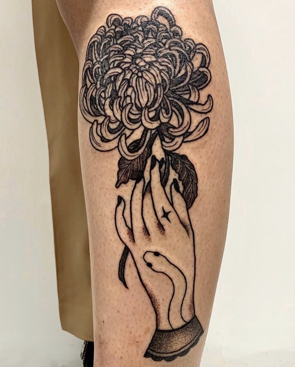 Detailed floral hand tattoo on leg