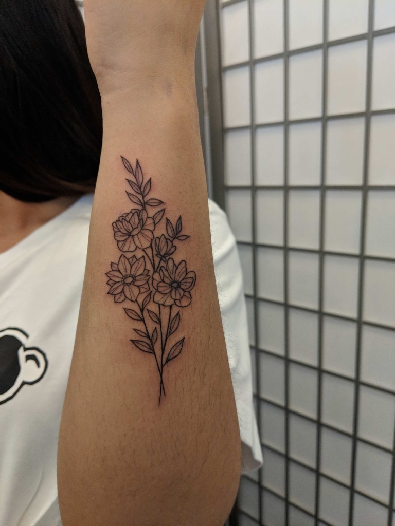 Floral linework tattoo on inner forearm