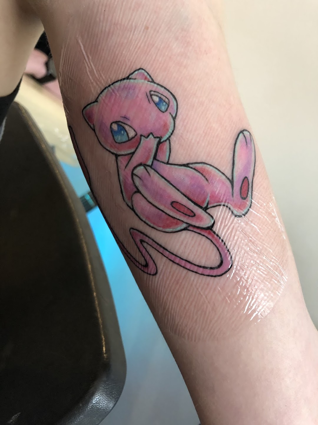 Pink character tattoo on arm